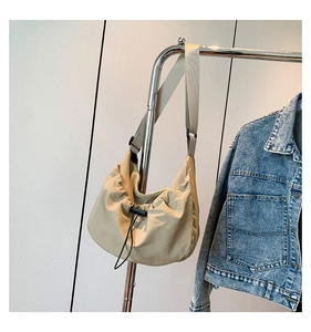 Detail of light beige nylon crescent bag featuring adjustable drawstring and wide strap