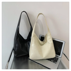 Detail view of large tote bag with geometric patchwork texture in black and cream beige