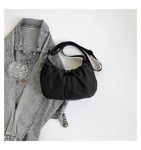 Detail of black nylon crescent crossbody bag with drawstring closure and soft pleated texture