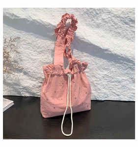Detailed macro of pink ruched tote bag with silver studs and white drawstring closure