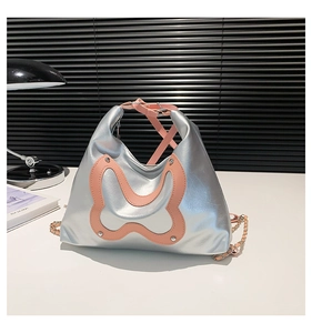 Detail of silver metallic shoulder bag with pink butterfly patch and chain strap