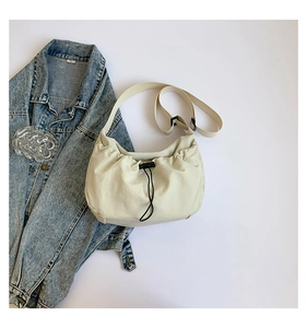 Detail of cream white nylon crossbody bag featuring drawstring closure and pleated texture