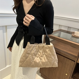 Sac fourre-tout beige matelassé avec surpiqûres en losange et poignées noires porté