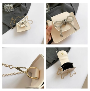 Detail view of cream chain bag featuring crystal bow, golden hardware and inner space