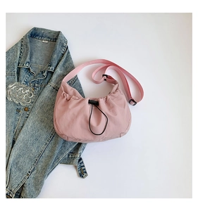 Pink nylon crescent crossbody bag with drawstring design and adjustable strap detail