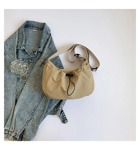 Detail of beige nylon half-moon bag featuring black drawstring closure and adjustable strap