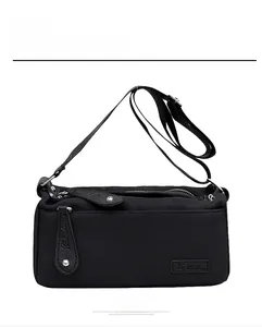 Front view of black canvas crossbody bag featuring textured leather pullers and wide strap