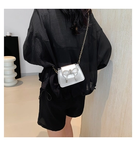 Detail of silver mini crossbody bag with rhinestone bow and gold chain strap