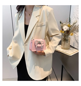 Detail of pink PU leather crossbody bag featuring a sparkling rhinestone bow buckle accent