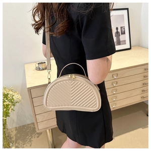 Dettaglio borsa a mezzaluna beige trapuntata con zip dorate e manico in pelle