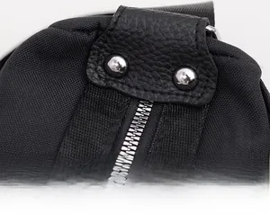 Detail of waterproof nylon bag showing leather trim, silver rivets, and metallic zipper