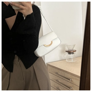 Selfie miroir montrant le sac sous le bras en cuir blanc avec fermoir croissant doré