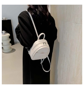 Vue arrière d'un mannequin portant le mini sac à dos en cuir crème dans une pièce
