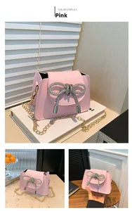Detail of pink crossbody bag featuring a large rhinestone bow and gold chain strap
