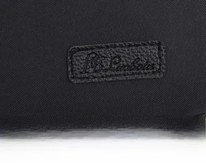 Detail of water-resistant nylon fabric and embossed leather brand logo on a black bag