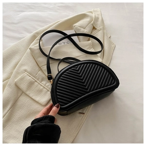 Dettaglio borsa a sella nera con trapuntatura a V su sfondo blazer beige