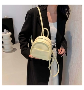 Vue détaillée du mini sac à dos en cuir jaune pâle avec fermetures éclair et bandoulières