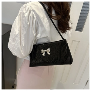 Détail d'un sac à bandoulière noir en similicuir plissé avec un nœud en métal argenté