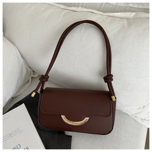 Détail d'un sac à main en cuir marron avec fermoir doré et bandoulière à nœuds élégante