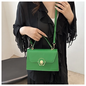 Detail of a bright green crossbody bag featuring a distinctive gold circular hollow lock