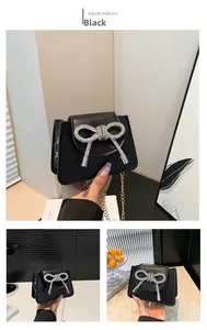 Detailed view of black mini crossbody bag featuring a large silver rhinestone bow and chain