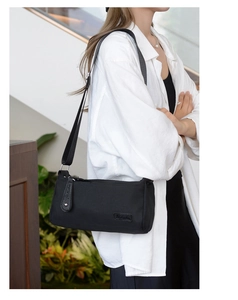 Detail shot of black nylon shoulder bag with adjustable strap worn by a model