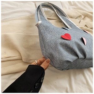 Detail of light blue denim tote bag with colorful heart patches and woven handles