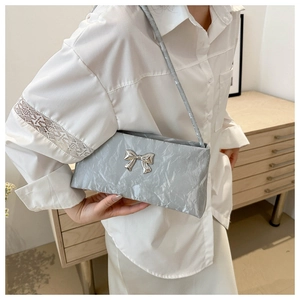 Détail du nœud métallique argenté sur le sac à main plissé gris texturé pour femme
