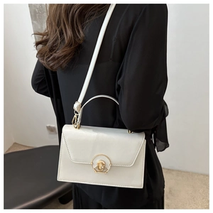 Detail view of cream white flap bag showing golden twist lock and leather texture