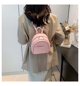 Mini sac à dos rose en similicuir avec fines bretelles porté par un mannequin chic
