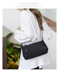 Detail of a black canvas crossbody bag with logo patch shown on a shoulder strap