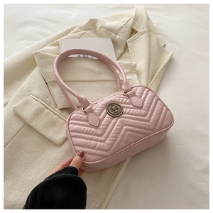 Detailed close-up of light pink quilted shoulder bag with V-shaped stitching and round emblem