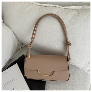 Détail d'un sac à bandoulière beige avec boucle dorée et bandoulière à nœuds élégants