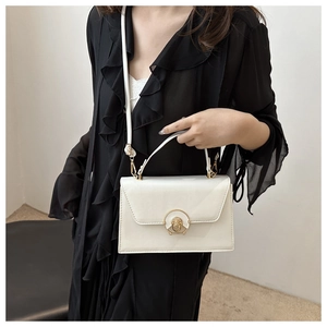 White minimalist square handbag featuring a glossy finish and a gold circular turn-lock closure