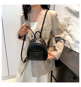 Mannequin asiatique portant un mini sac à dos noir en similicuir dans un intérieur moderne