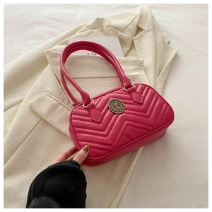 Detail of rose pink quilted shoulder bag featuring a vintage gold medallion and stitching