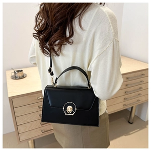 Detail of black matte leather crossbody bag with gold metal ring lock and top handle