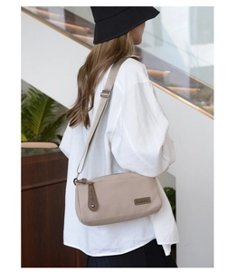 Beige nylon crossbody bag with brown leather accents on white oversized shirt outfit
