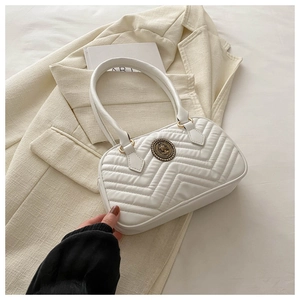 Detail of white quilted tote bag featuring a vintage metal buckle on a beige suit background