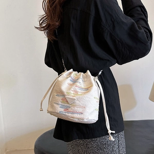 Borsa a secchiello bianca con ricami colorati e tracolla a catena indossata da modella