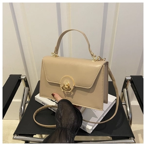 Detail of beige faux leather handbag with round gold lock and slim shoulder strap