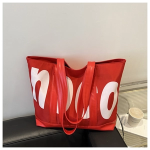 Détail du grand sac cabas rouge avec lettres hoco blanches sur un canapé en cuir