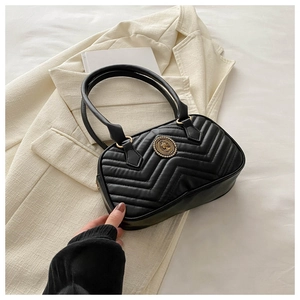 Close-up of black quilted shoulder bag featuring a vintage gold circular logo emblem