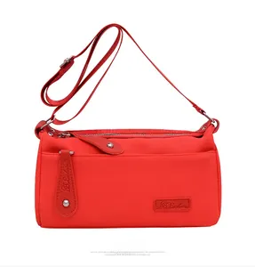 Detail of red nylon crossbody bag with adjustable wide strap and metallic zip pocket