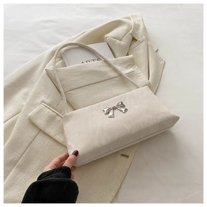 Détail du fermoir noeud en métal argenté sur un sac à bandoulière en cuir texturé