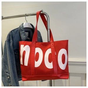 Détail du grand cabas rouge en toile avec lettrage noco blanc et poignées en cuir