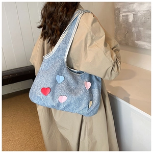 Detail of light blue denim tote bag with colorful heart patches and silver trim