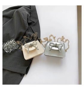 Detail of elegant crossbody bags with rhinestone bows in creamy white and silver finish