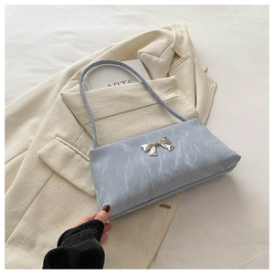 Détail du sac bandoulière bleu clair avec texture marbrée et nœud métallique argenté