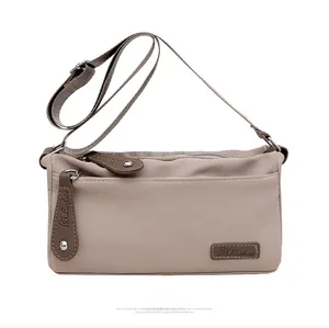 Detail view of water-resistant nylon shoulder bag with leather zipper pulls and logo
